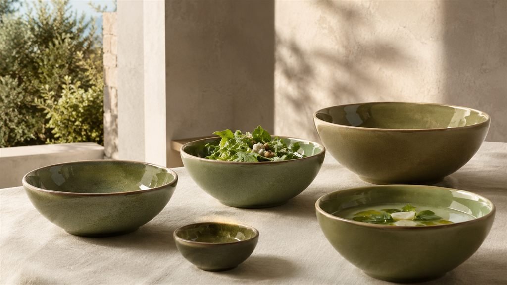 Sage green Verllage stoneware bowls in different sizes on a linen tablecloth in soft evening light